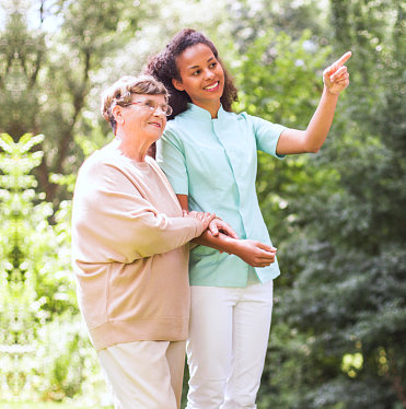 caregiver walking with senior woman in the park